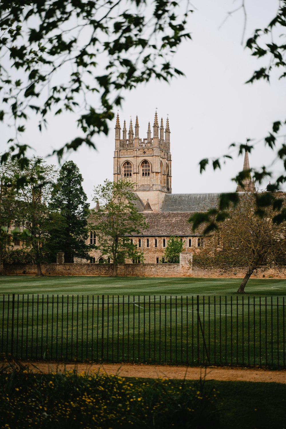 a large building with a tall tower next to a lush green field