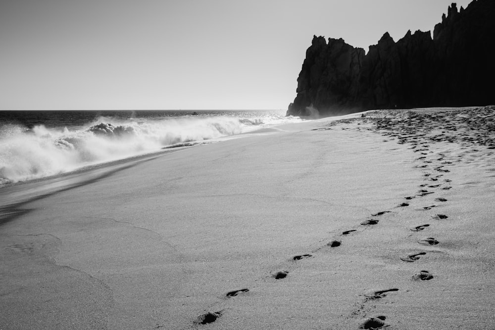 Una foto en blanco y negro de una playa con huellas en la arena