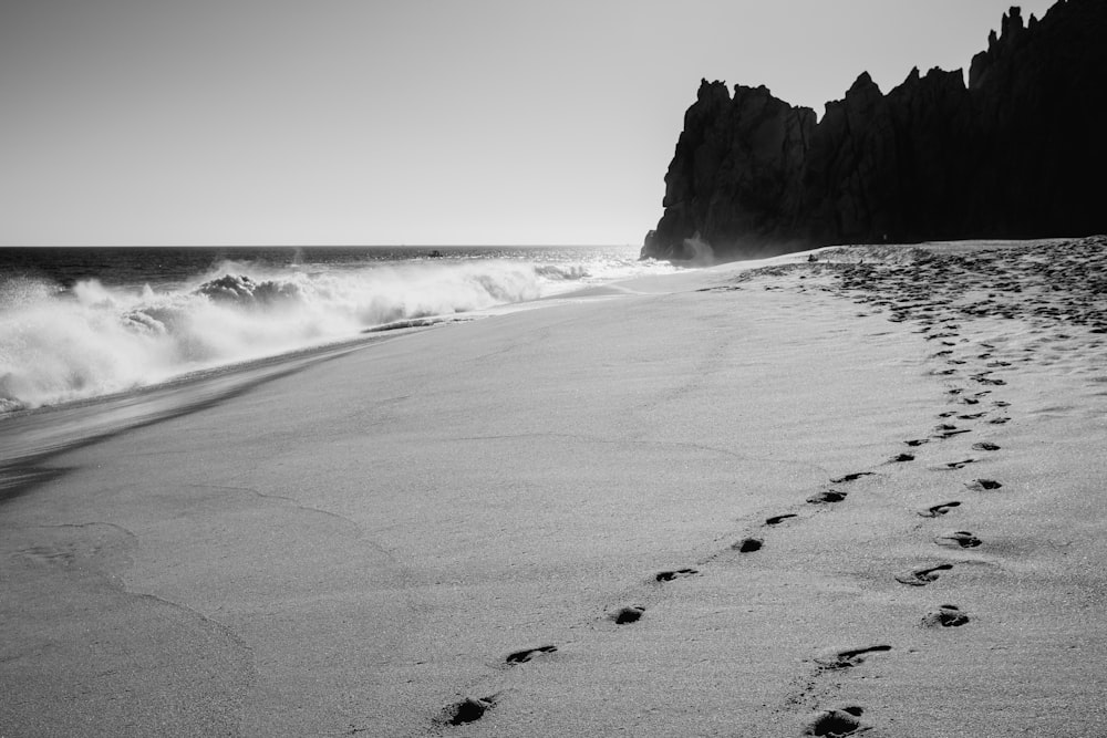 a black and white photo of a beach with footprints in the sand