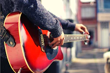 a person playing a red guitar on a city street