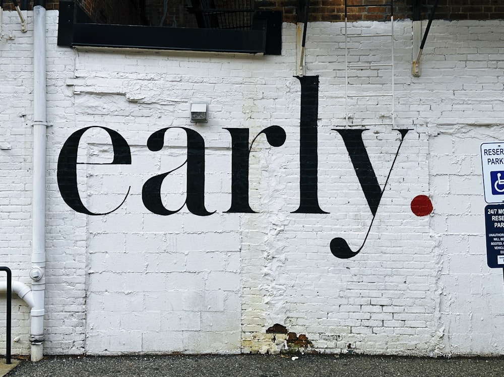 a white brick wall with a black and red word painted on it