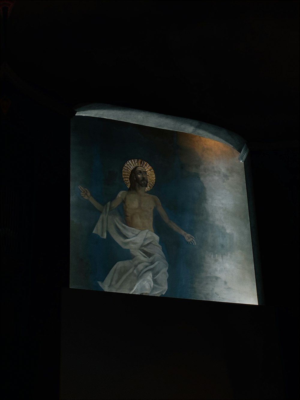 a painting of jesus on a wall in a dark room