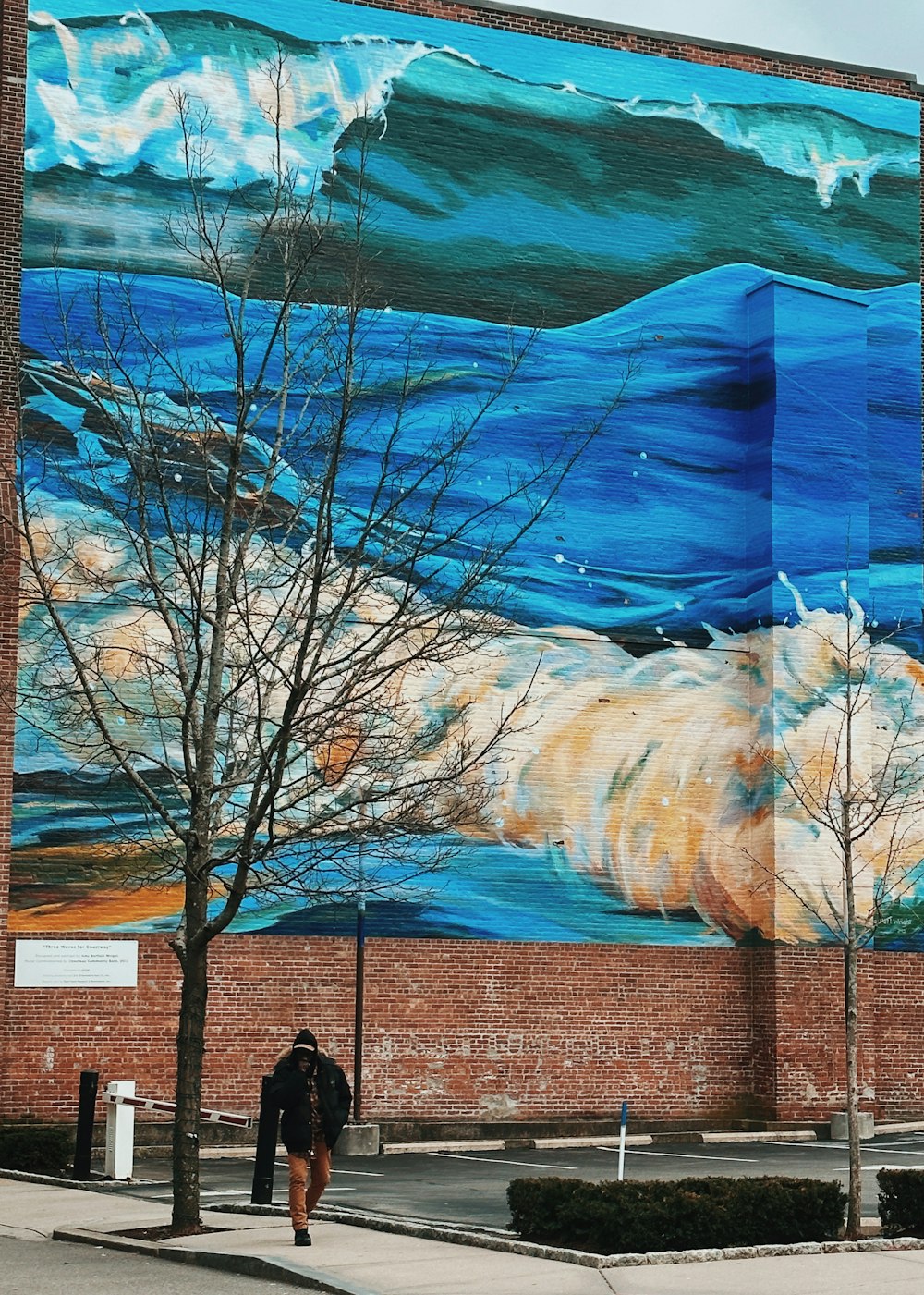 a man walking past a large painting on the side of a building
