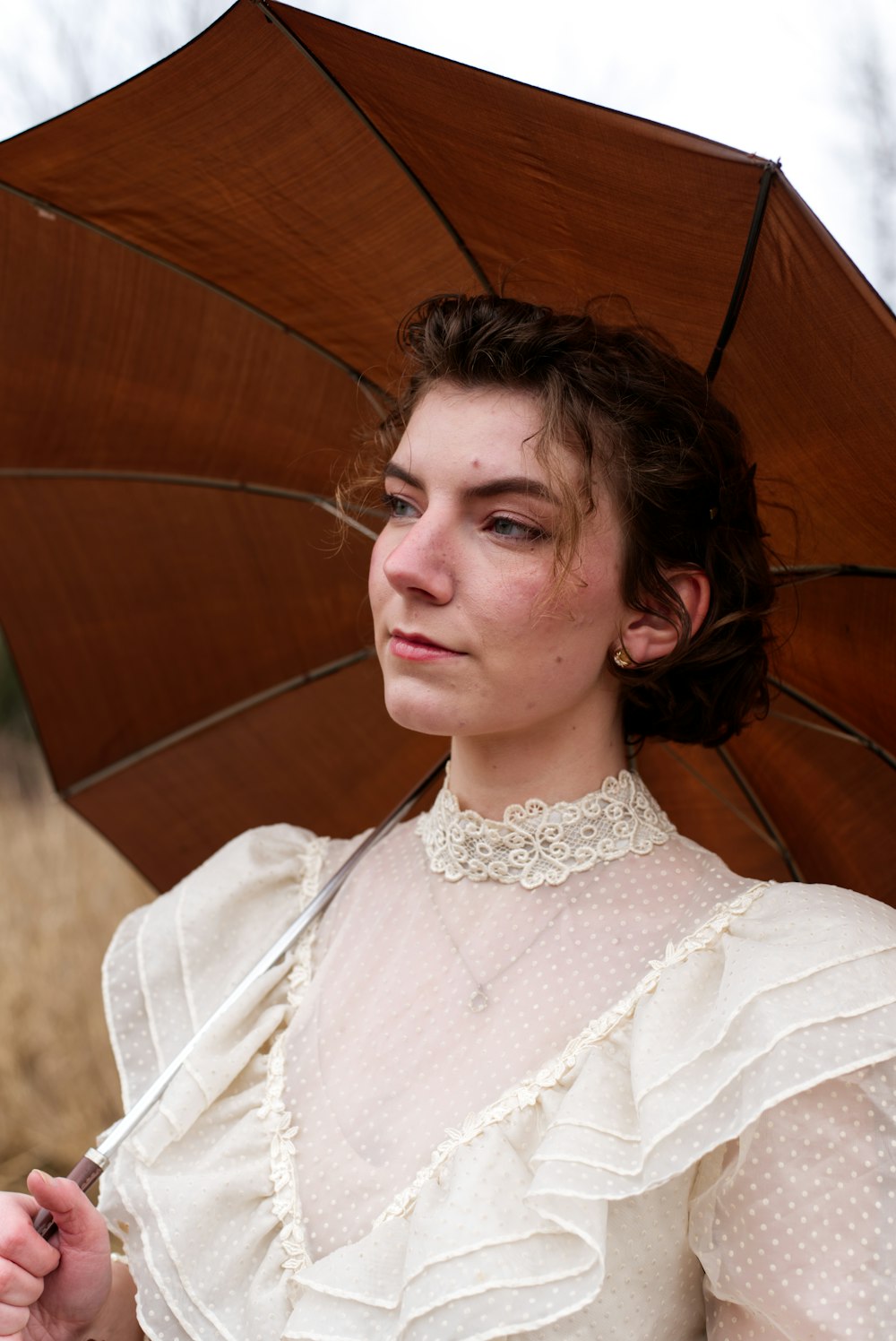 a woman in a white dress holding a brown umbrella