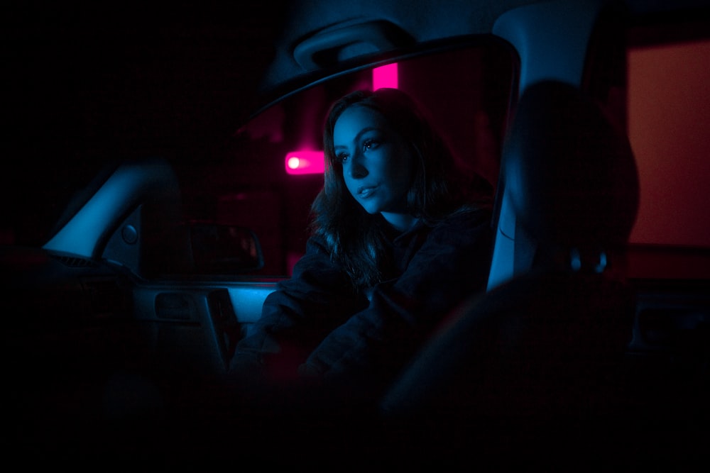 a woman sitting in a car in the dark