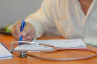 a person writing on a piece of paper with a stethoscope