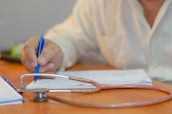 a person writing on a piece of paper with a stethoscope
