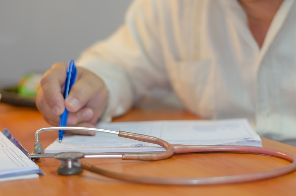a person writing on a piece of paper with a stethoscope