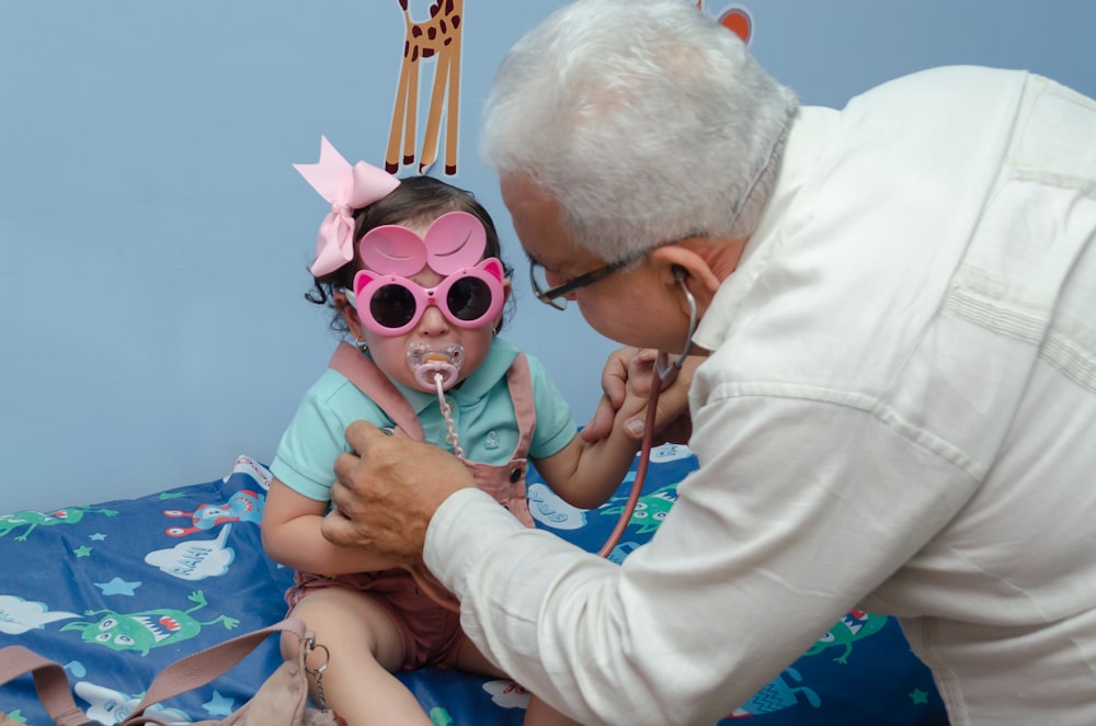 a little girl is getting her teeth brushed by an older man