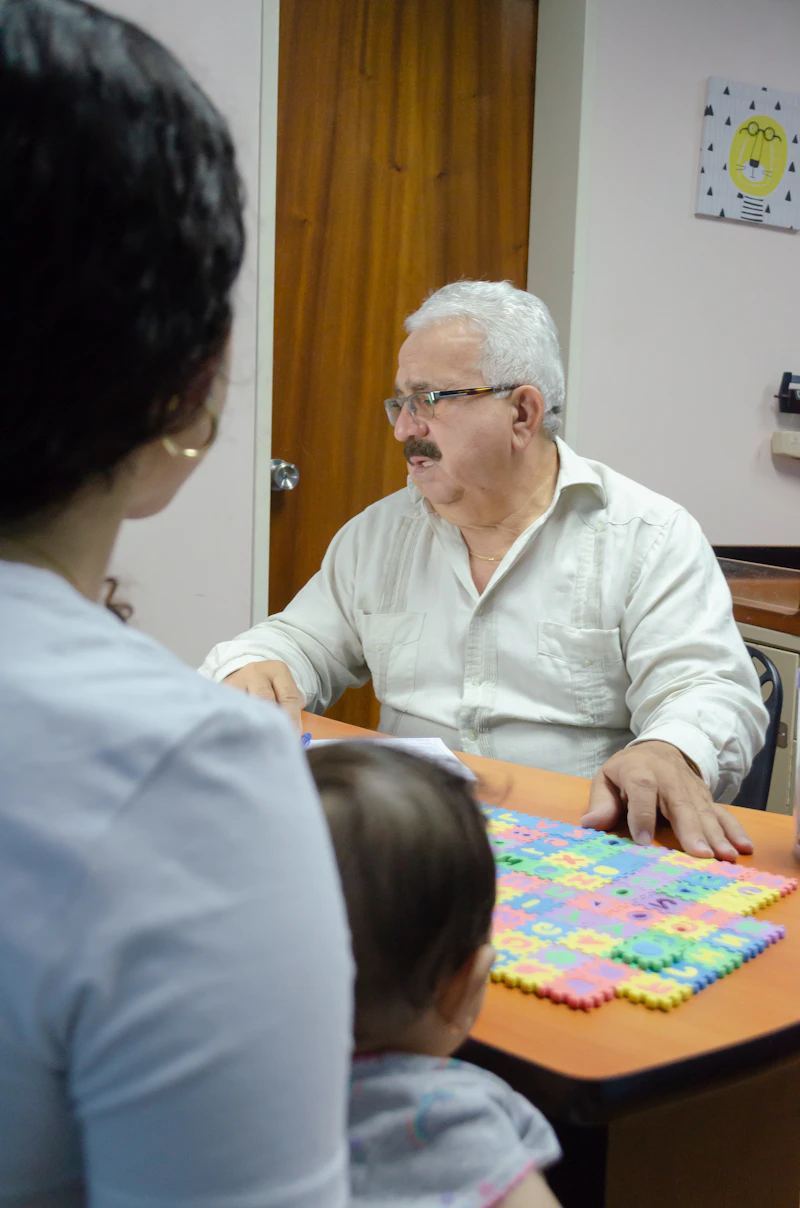 A speech-language pathologist works one-on-one with a young patient at a table