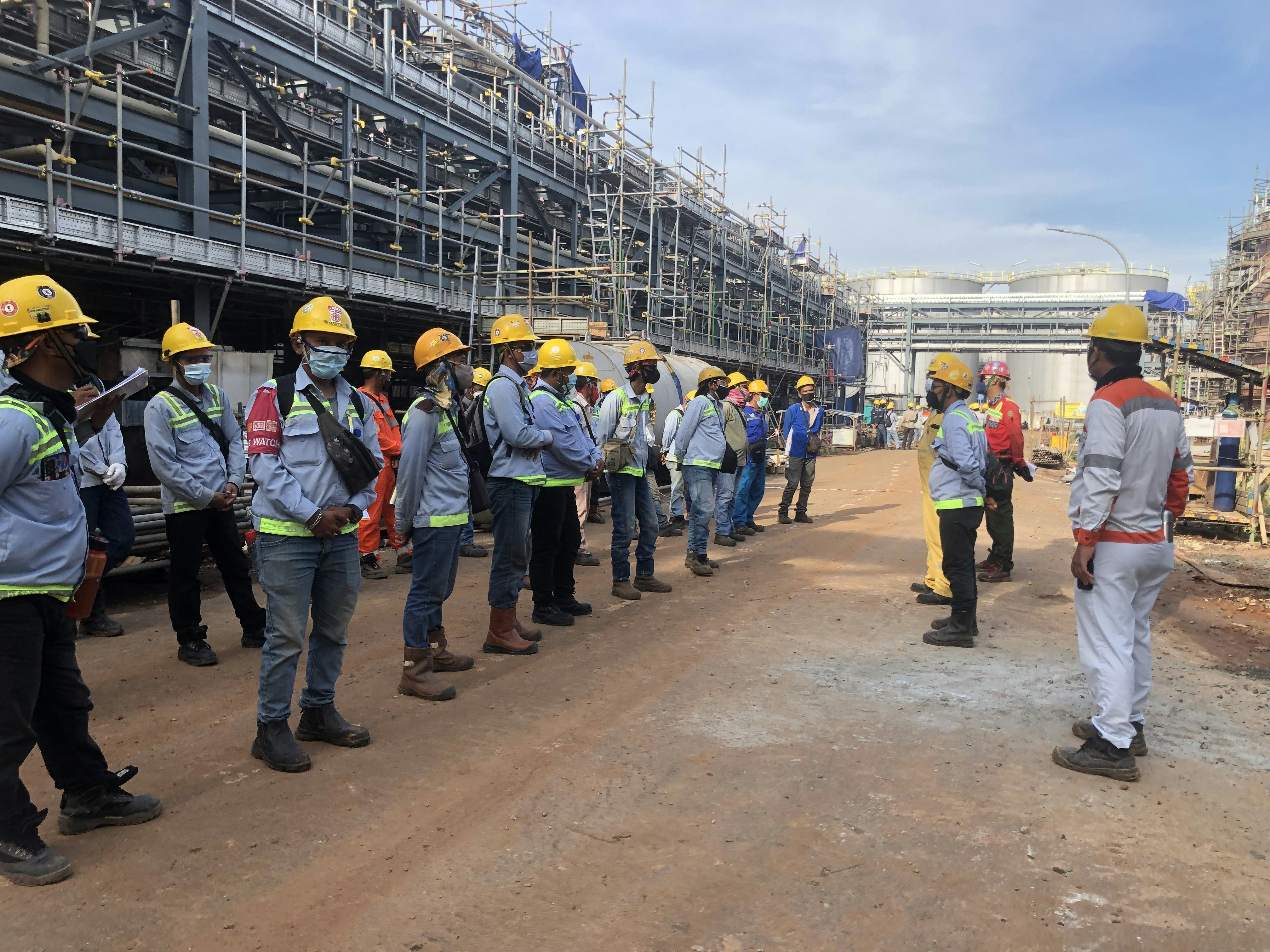 Workers in safety helmets at an industrial facility discussing workplace safety regulations