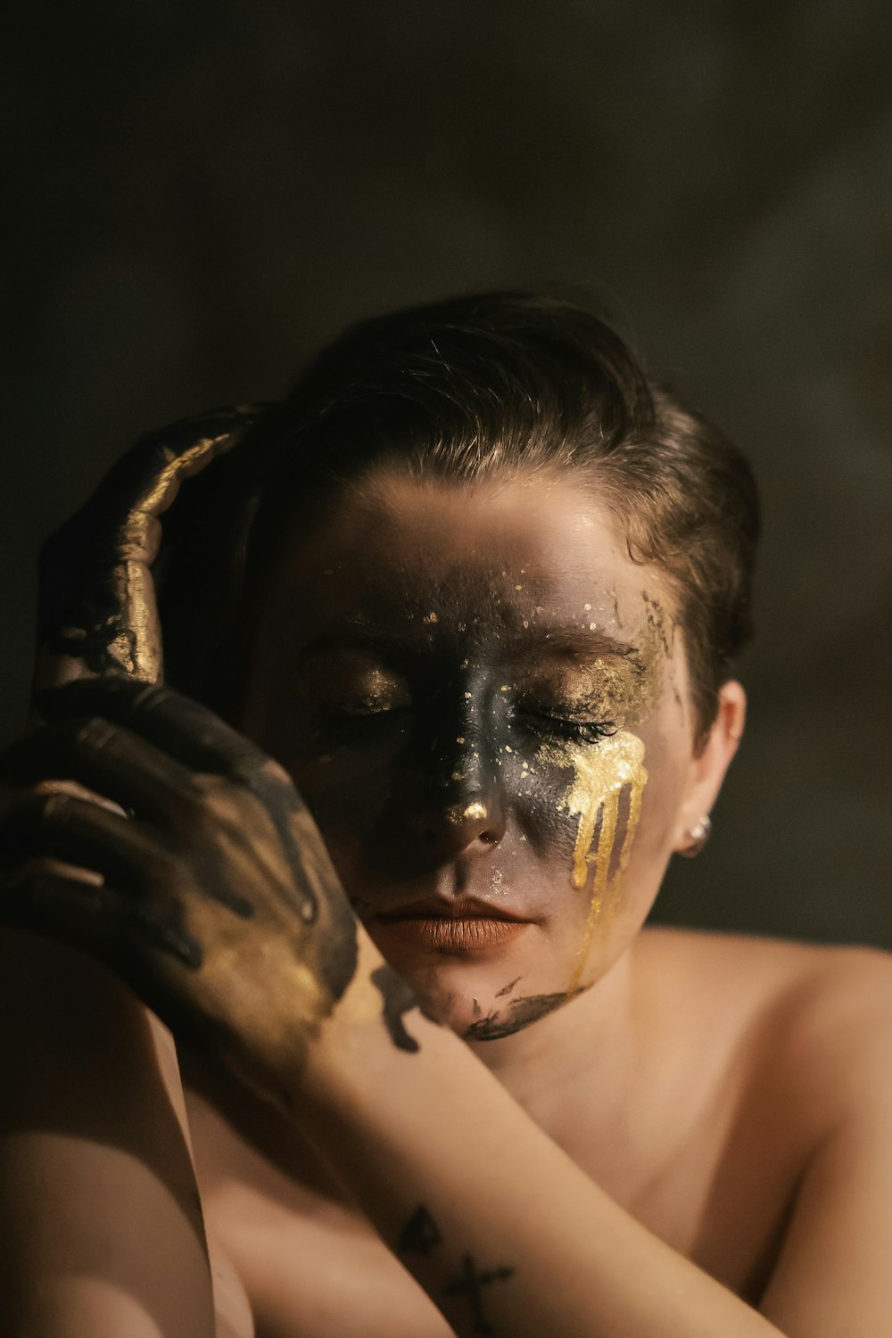 a woman with gold paint on her face and hands