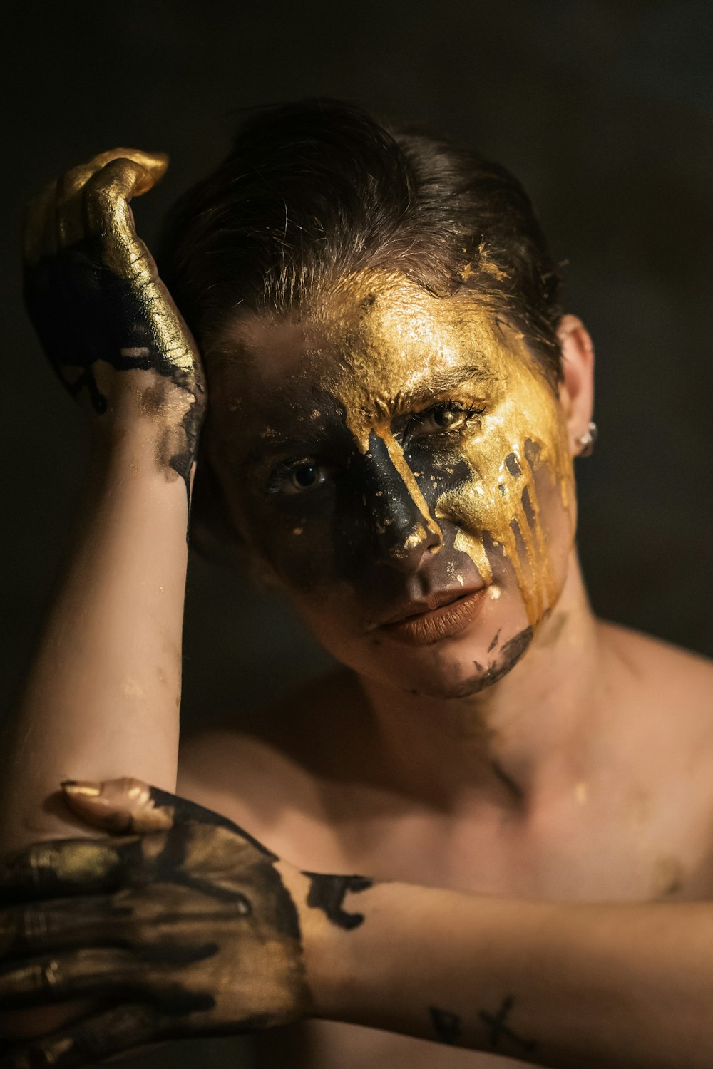 a man with gold paint on his face and hands
