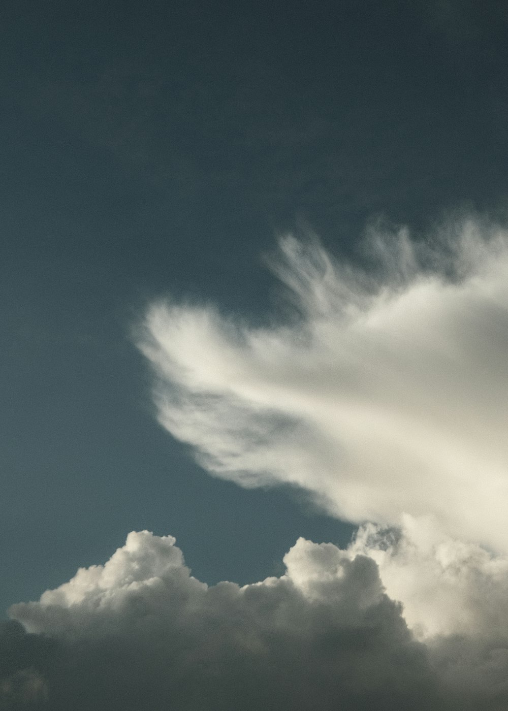 a plane flying through a cloudy blue sky