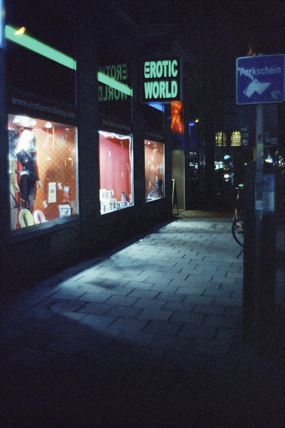 a dark street at night with storefronts lit up
