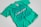 A turquoise t-shirt with an intricate blue graphic design and text on the front. The design includes various abstract shapes, musical elements, and patterns. The text reads 'New Breed of Deep House' with additional words above it that are difficult to discern.