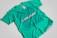A turquoise t-shirt with an intricate blue graphic design and text on the front. The design includes various abstract shapes, musical elements, and patterns. The text reads 'New Breed of Deep House' with additional words above it that are difficult to discern.