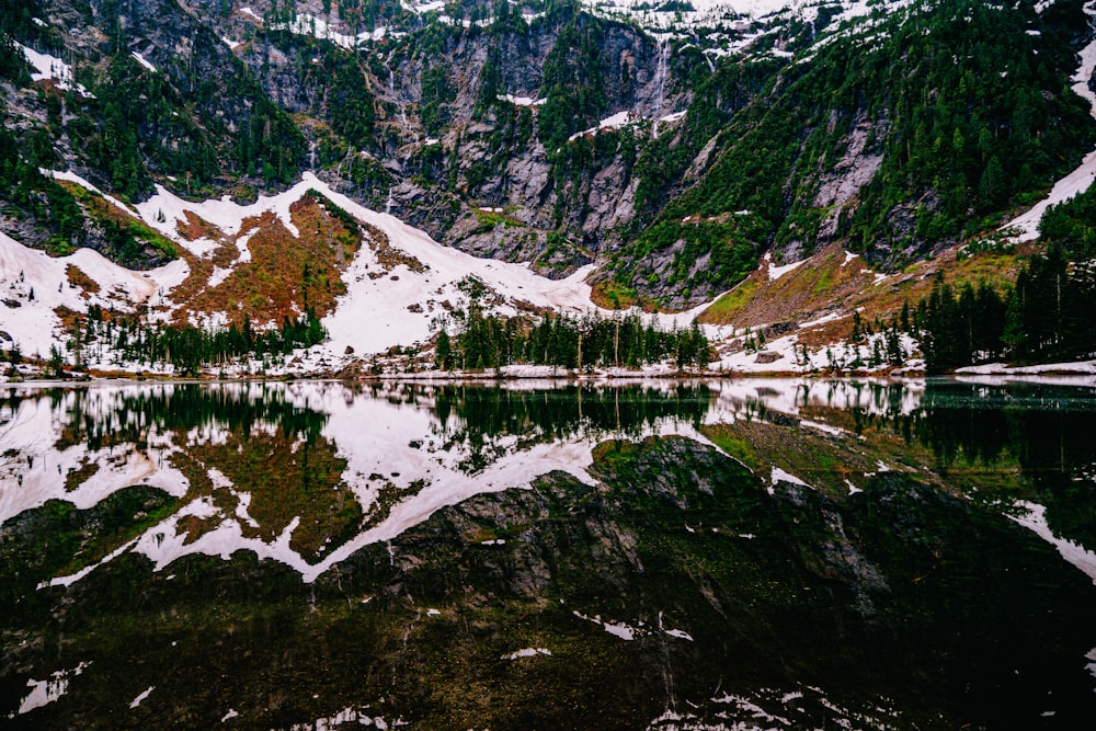 a mountain range with a lake surrounded by snow