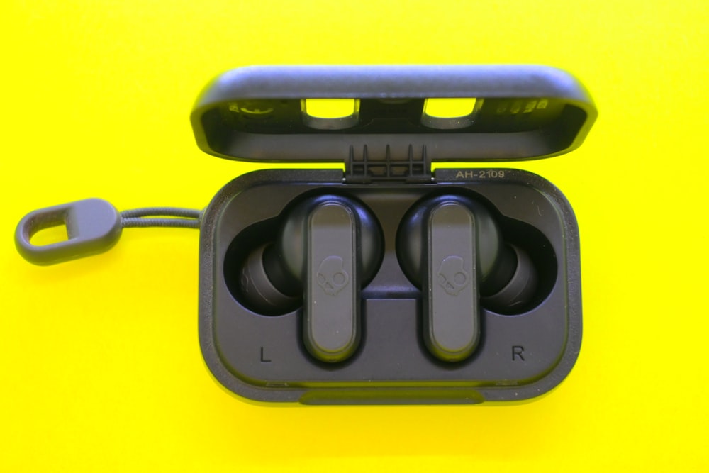 a pair of ear buds in a case on a yellow background