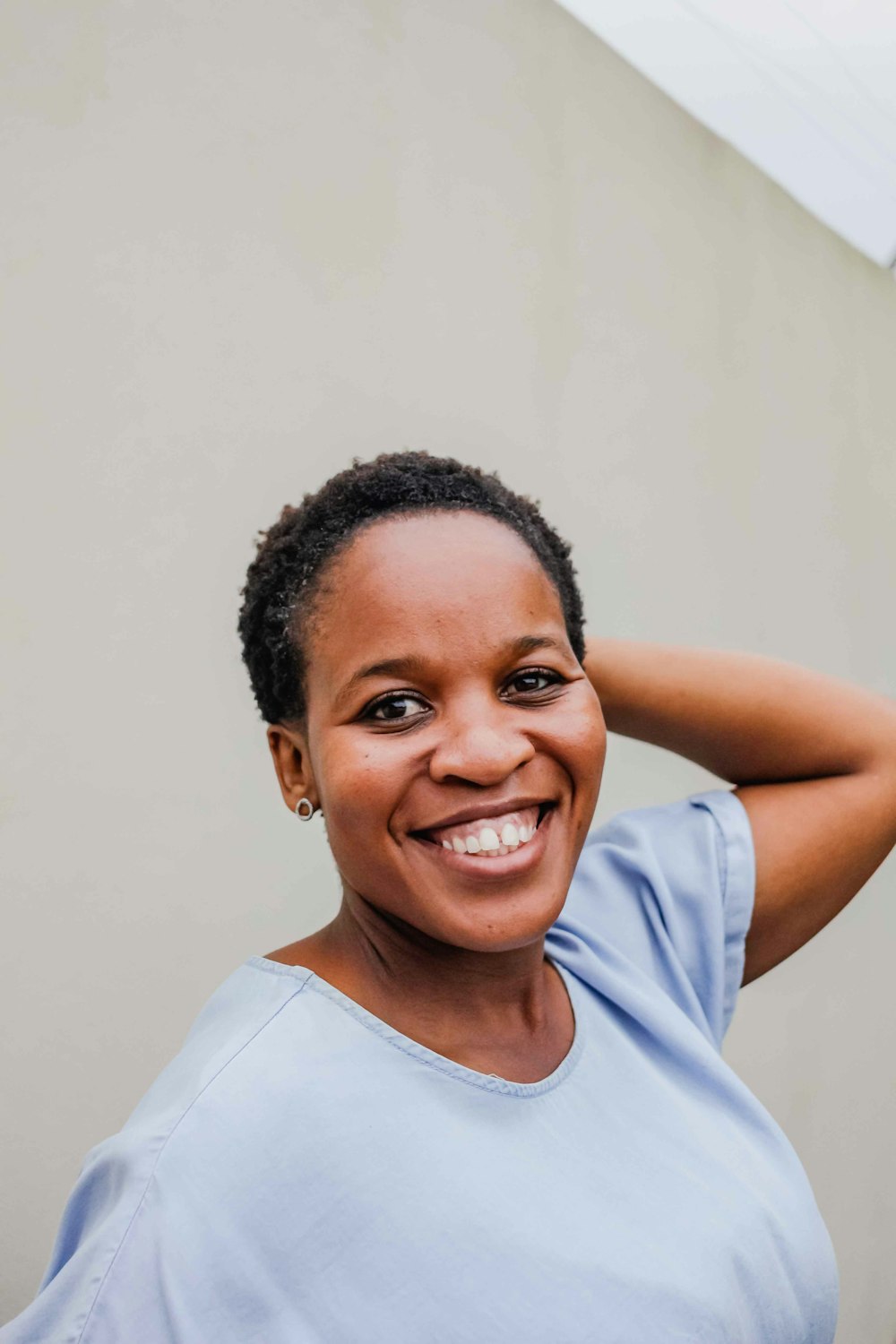 a smiling woman with her hand on her head