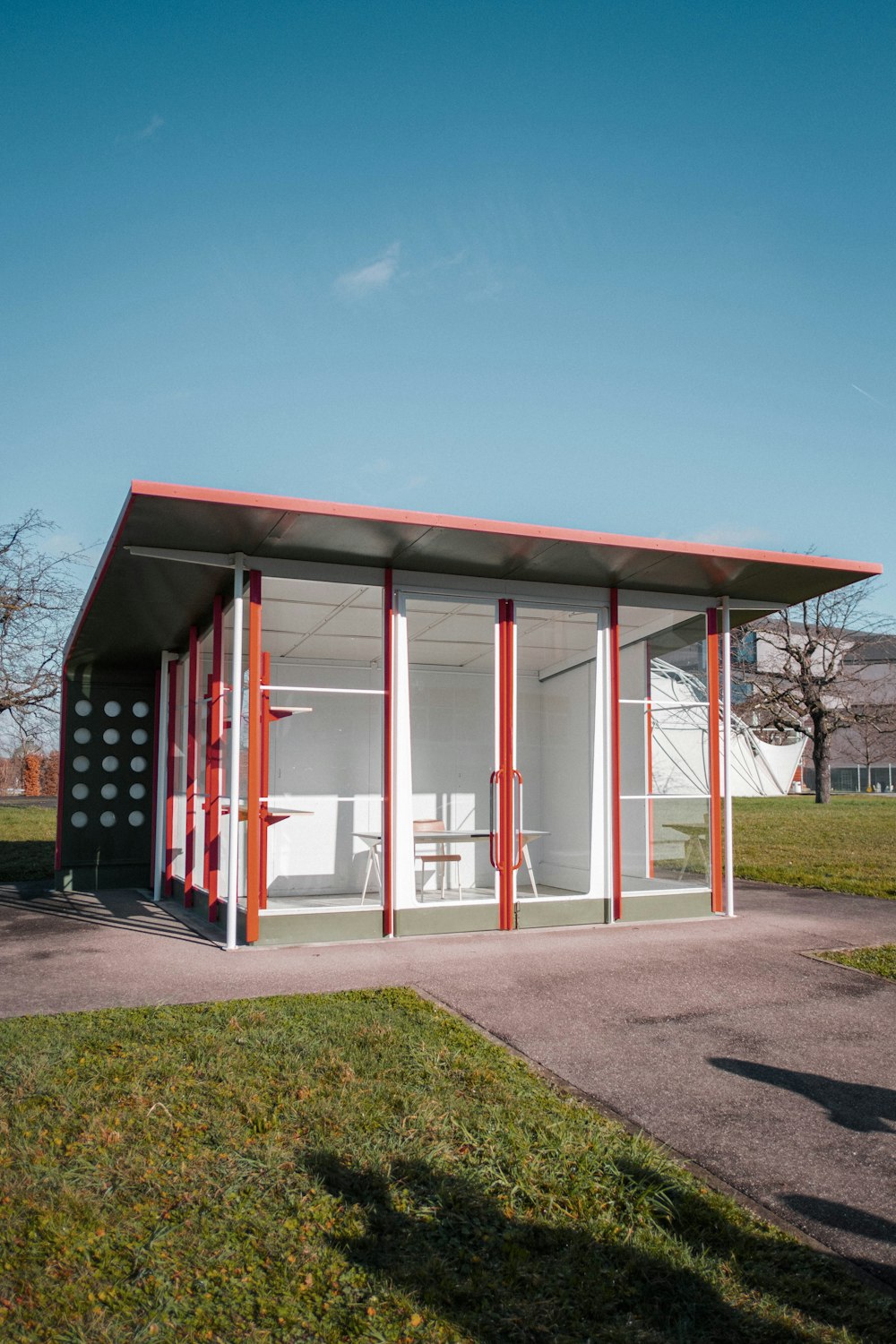 a small red and white building sitting on top of a grass covered field