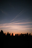 A sunset view behind a crowd gathered for an open-air worship session.