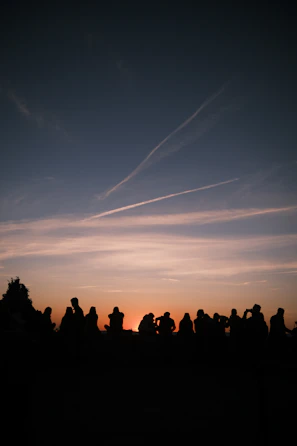 A sunset view behind a crowd gathered for an open-air worship session.