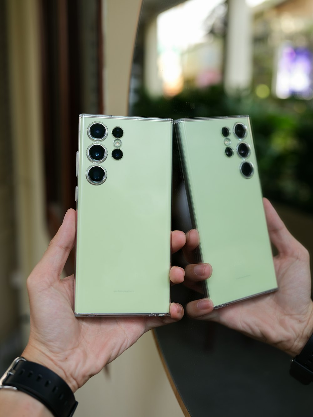a pair of hands holding two green cell phones