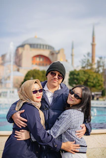 A family smiling happily in front of the iconic Blue Mosque in Madina, capturing a joyful travel moment.