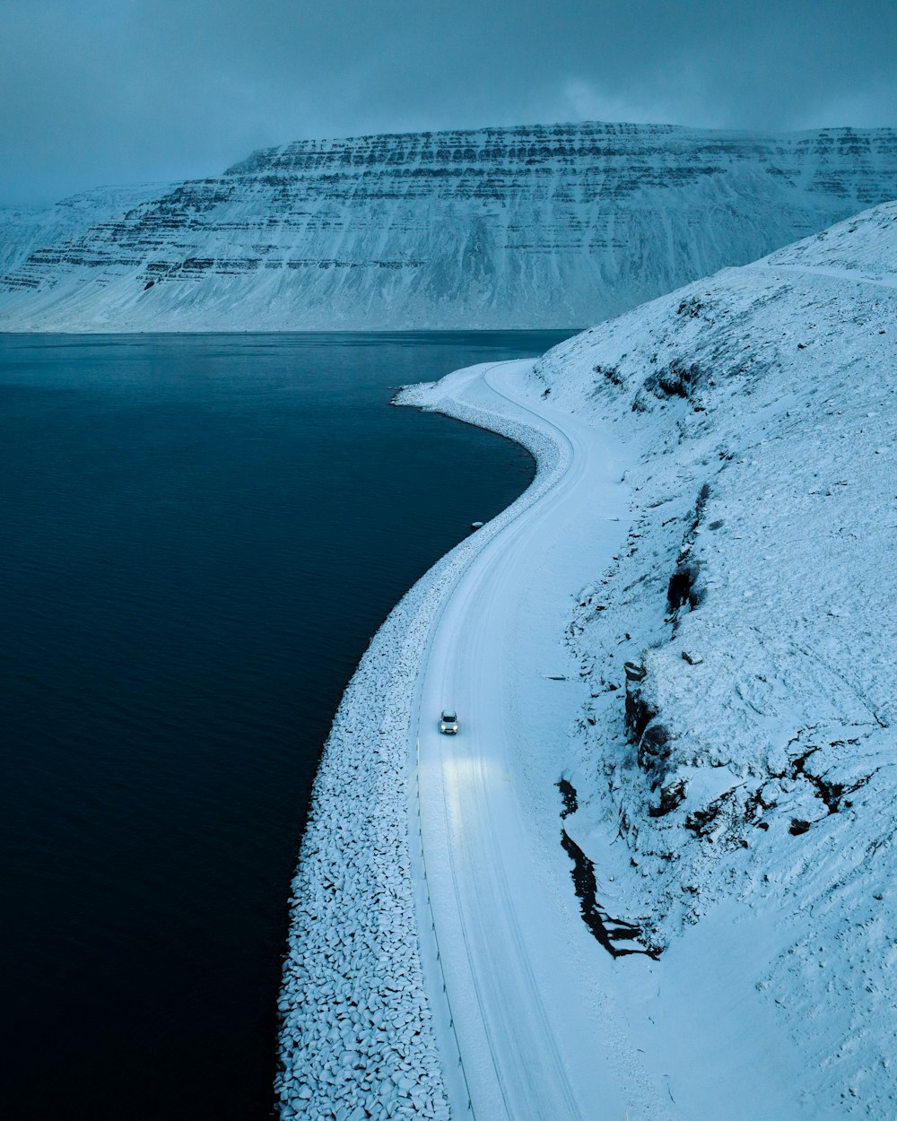 a snow covered hill next to a body of water