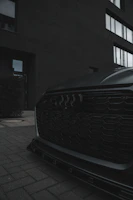 Close-up of a sleek supercar's aggressive front grille under moody lighting.