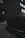 A close-up of a car's front grille with a sleek, modern design, including a distinctive logo. The setting is urban, with a brick exterior of a building and large windows in the background. The overall ambiance is moody with low lighting.