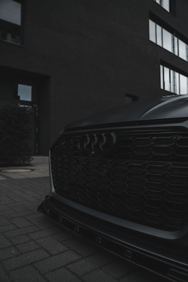 Close-up of a glossy electric vehicle front grille with illuminated logo under soft lighting.