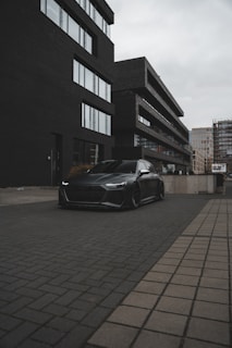 A sleek black car parked in an urban setting, showcasing modern design.