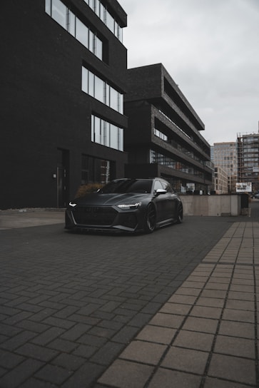 A sleek black car parked in an urban setting, showcasing modern design.