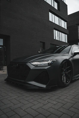 A sleek black car parked in a clean, modern driveway under soft lighting.