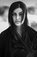Portrait of a woman with textured hair and intense gaze against a dark background.