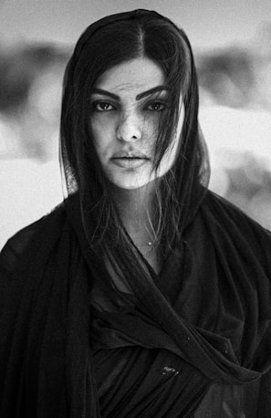 Portrait of a woman with textured hair and intense gaze against a dark background.