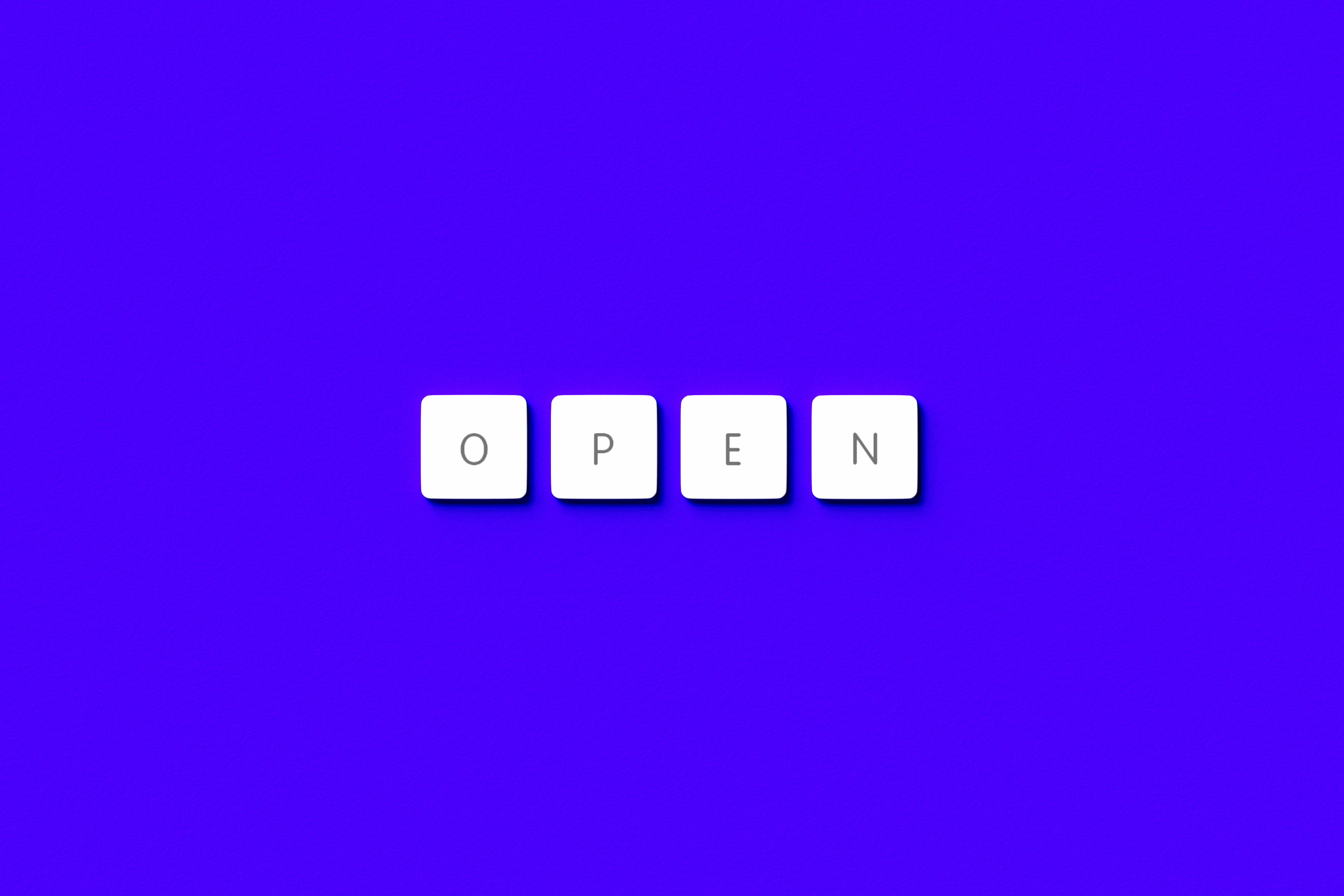 the word open spelled with scrabble letters on a purple background