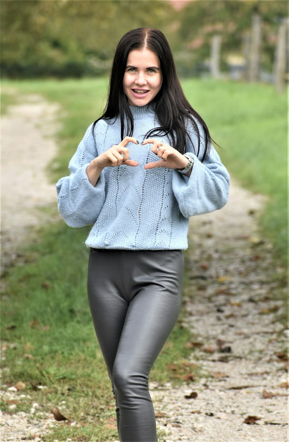 a woman in a blue sweater is walking down a path