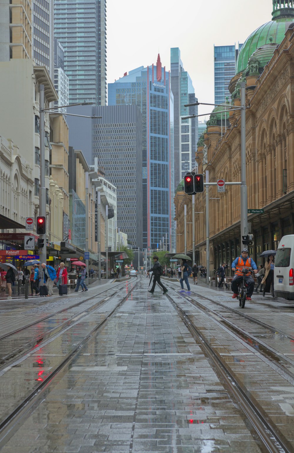 uma rua molhada da cidade com pessoas andando nela