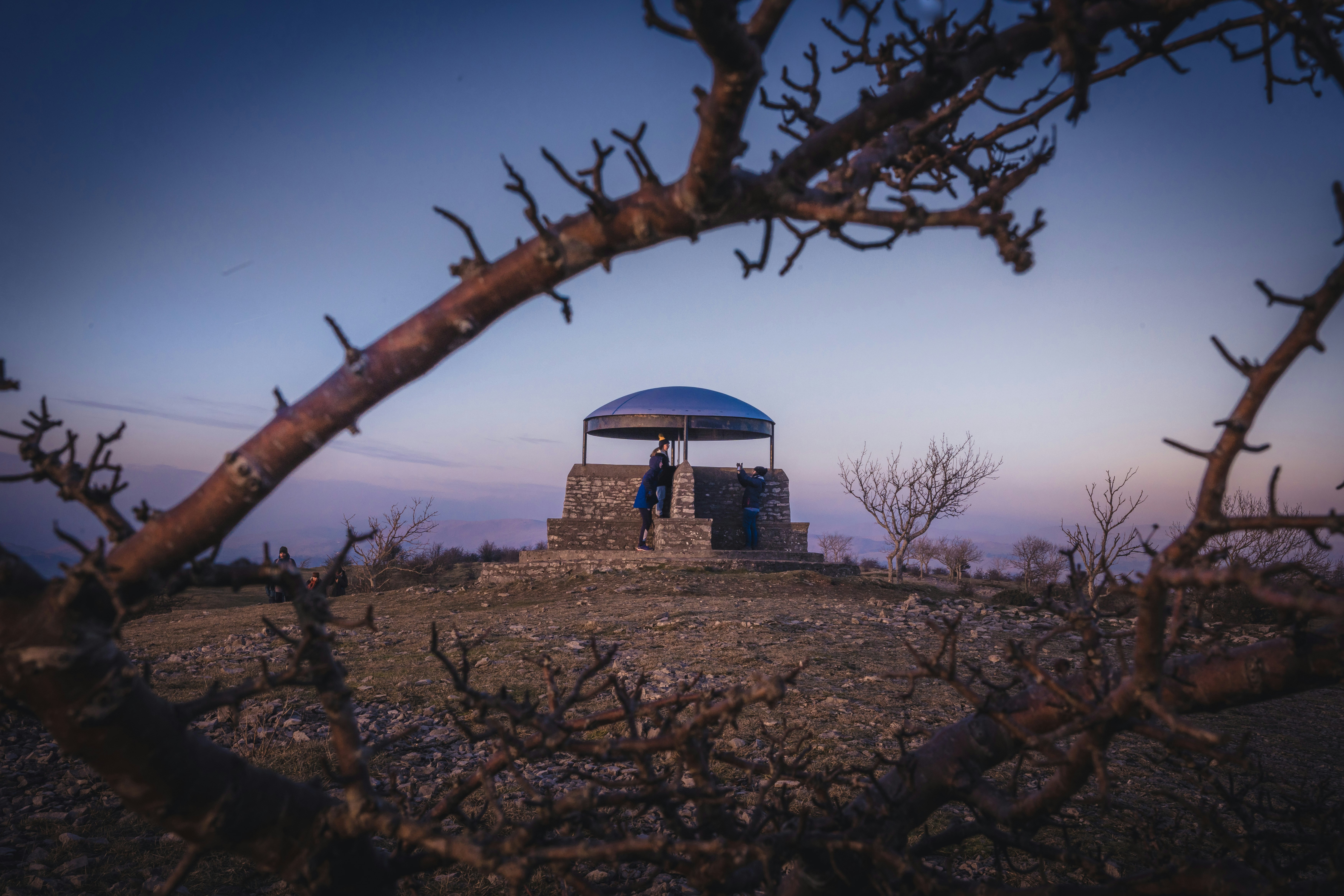 Ein Mann steht unter einem blauen Regenschirm auf einem Hügel