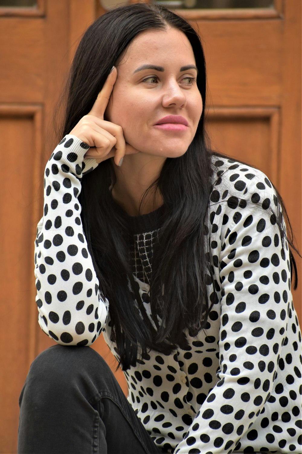 a woman sitting in front of a wooden door