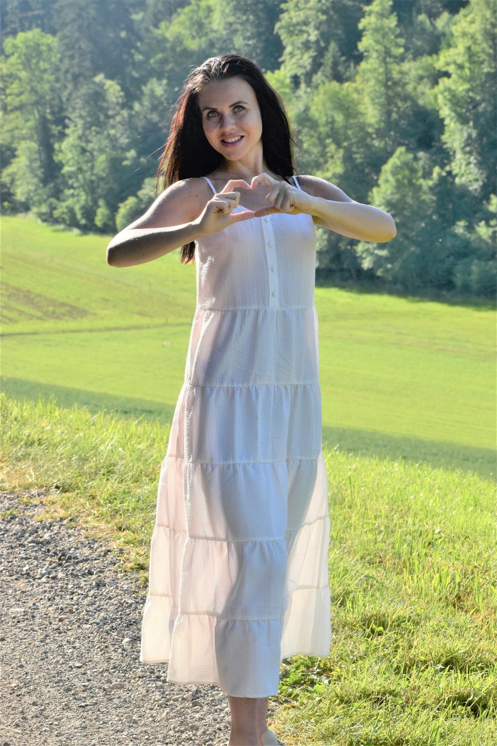 a woman in a white dress is pointing at the camera