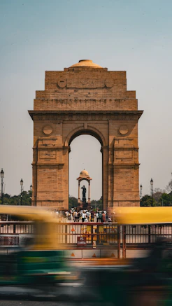 a yellow bus driving past a large stone arch