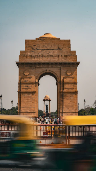 a yellow bus driving past a large stone arch