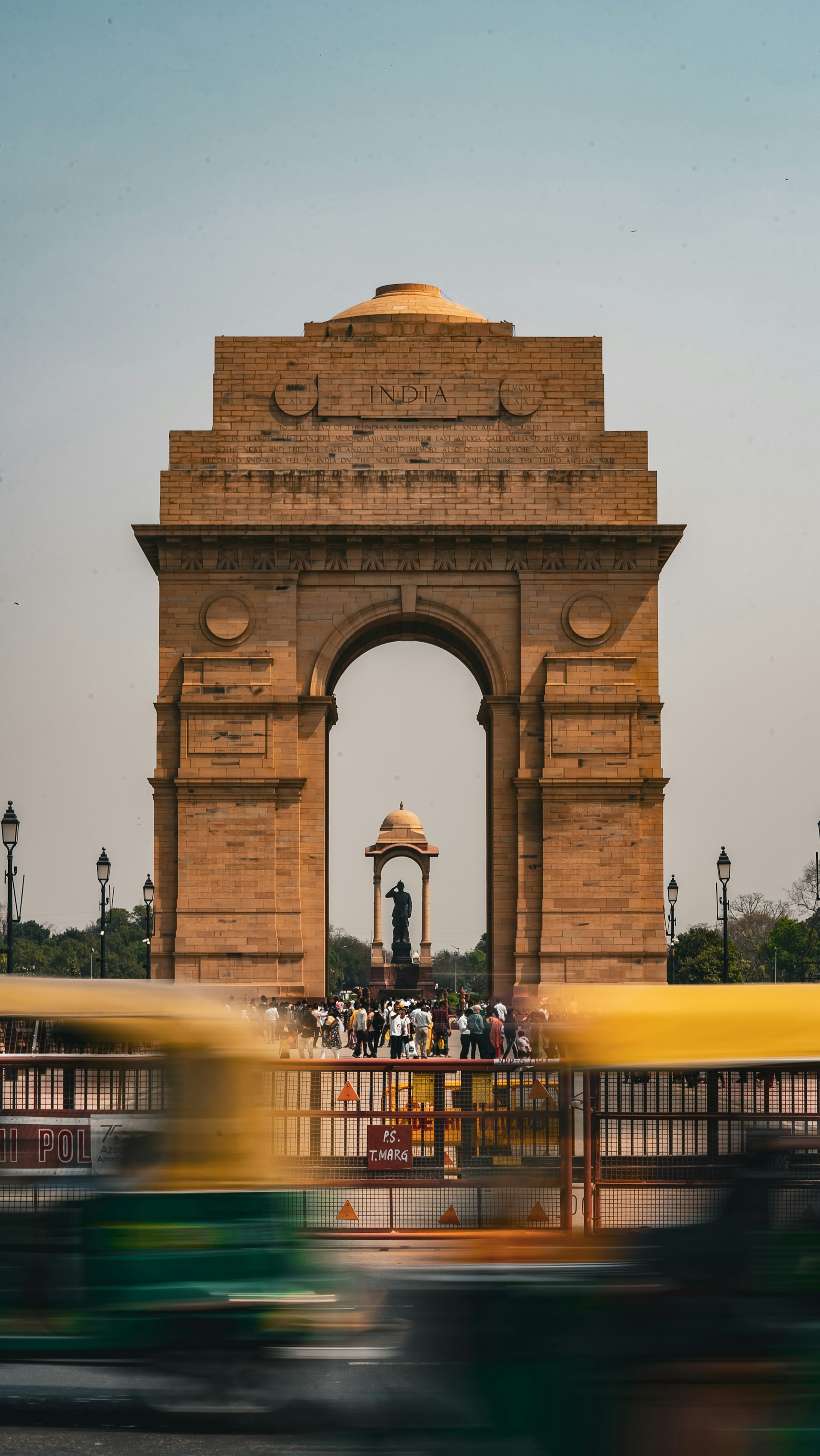 a yellow bus driving past a large stone arch