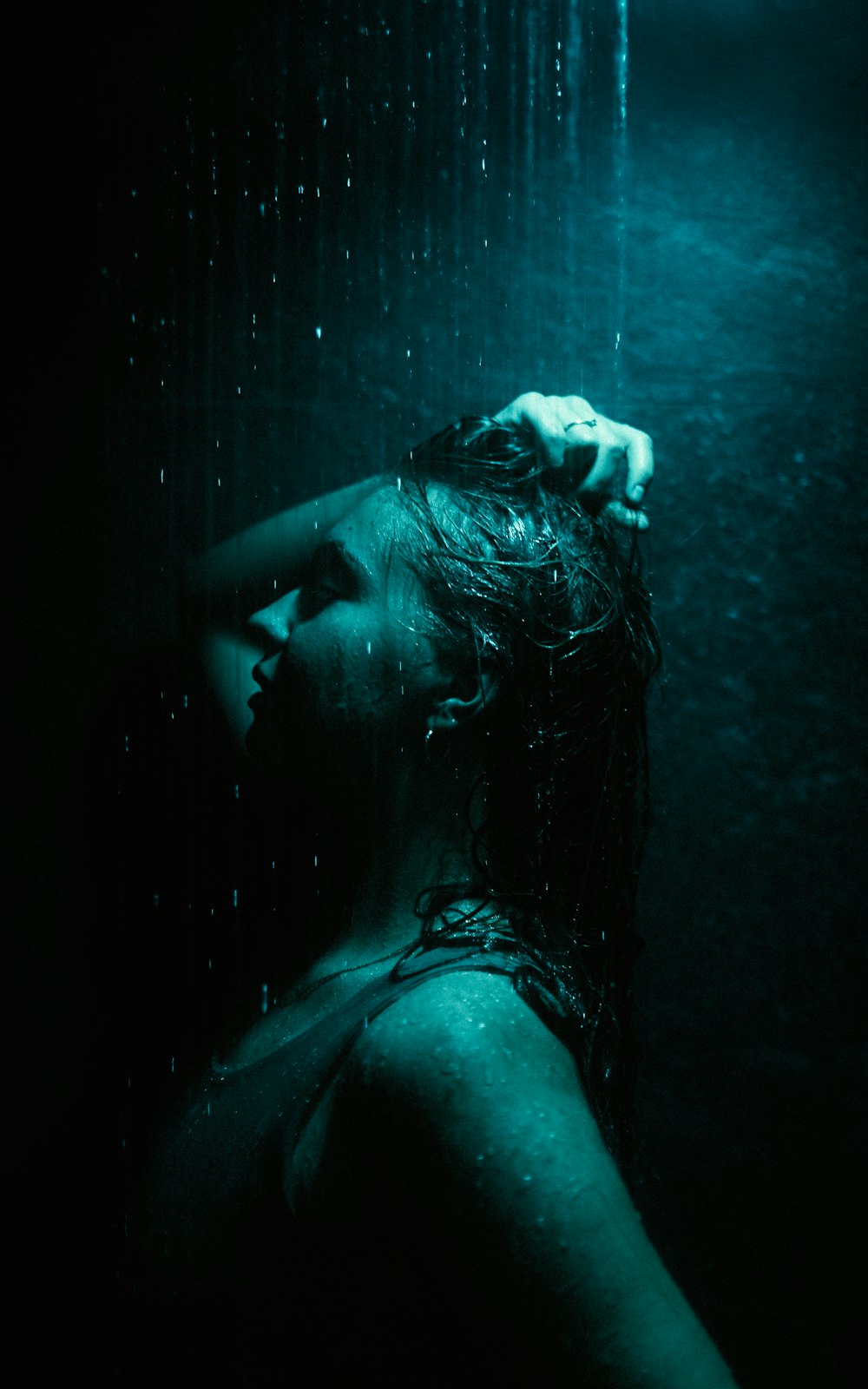 a woman standing under a rain shower in the dark