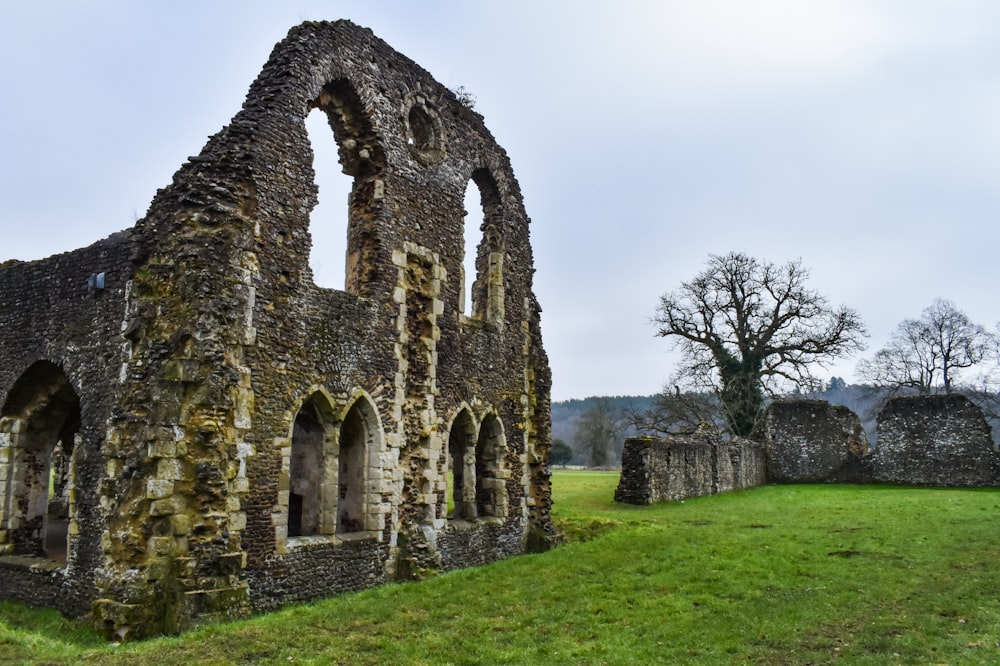 an old stone building with a green field in front of it