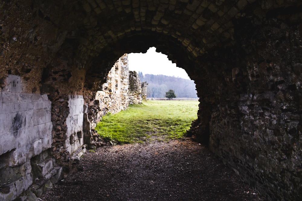 a stone tunnel with a grassy field in the background